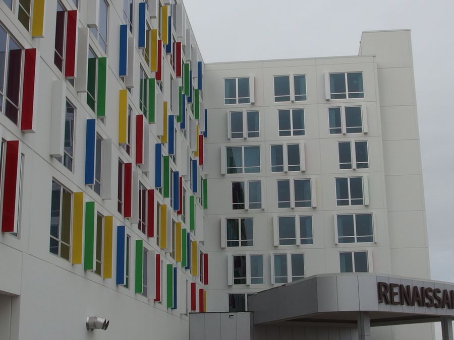 Photograph of the Renaissance Edmonton Airport Hotel: a white facade with red, yellow, blue and green window fins above the entrance canopy