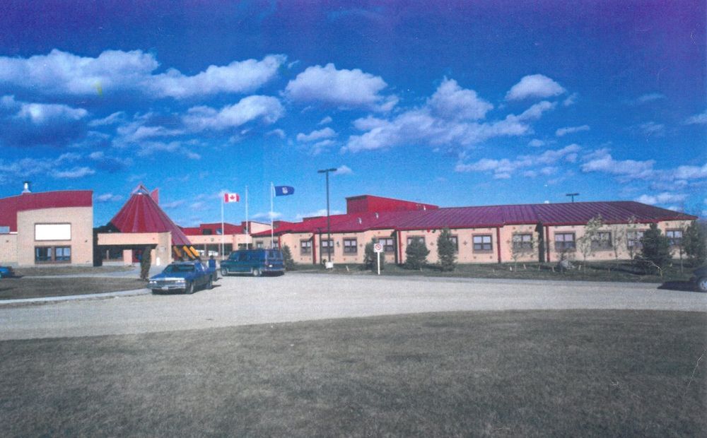 Archive photograph of the original Alexis School, a long low building with a red conical entrance