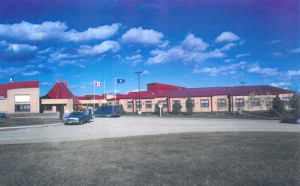 Archive photograph of the original Alexis School, a long low building with a red conical entrance